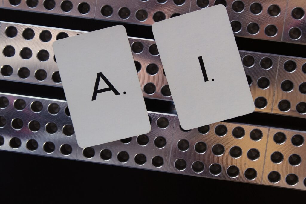 Letras A. e I. escritas em cartões brancos sobre faixa de metal.