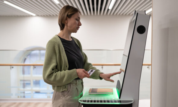 Mulher de meia idade usando terminal de autoatendimento no espaço da biblioteca digital, registrando livro, pesquisando e selecionando literatura ou navegando em catálogo. Tecnologias inovadoras em bibliotecas