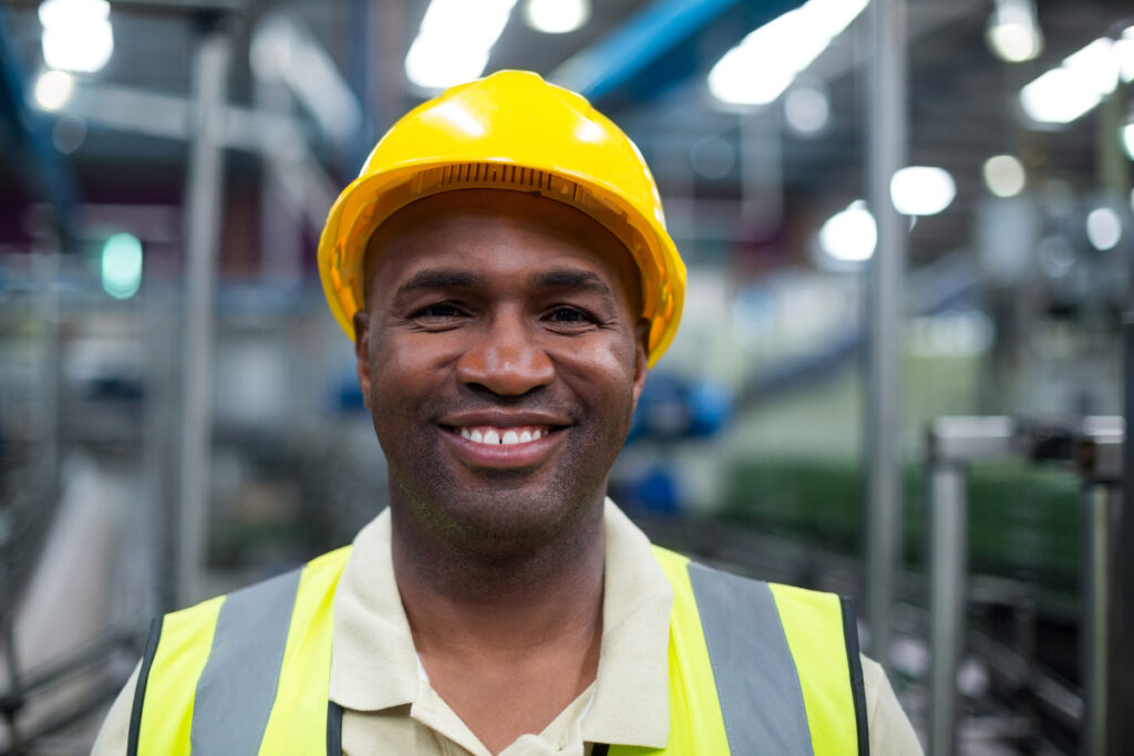 Trabalhador sorrindo em fábrica; desemprego cai a menor nível em 8 anos