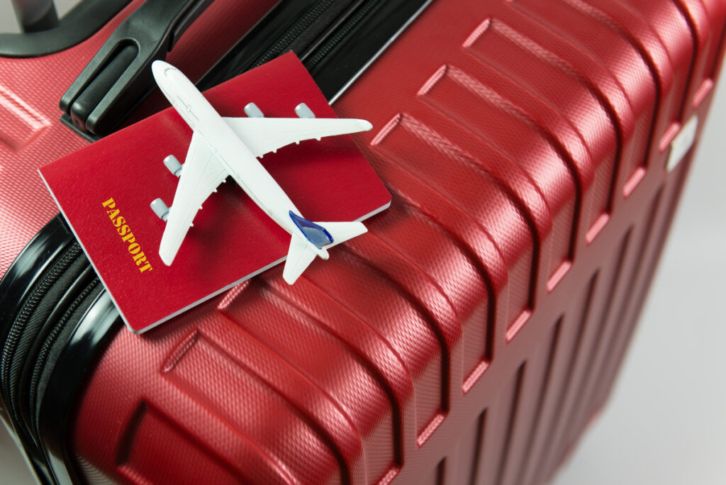 imagem de avião em miniatura em cima de passaporte e mala de viagem; 123 Milhas tem recuperação judicial suspensa