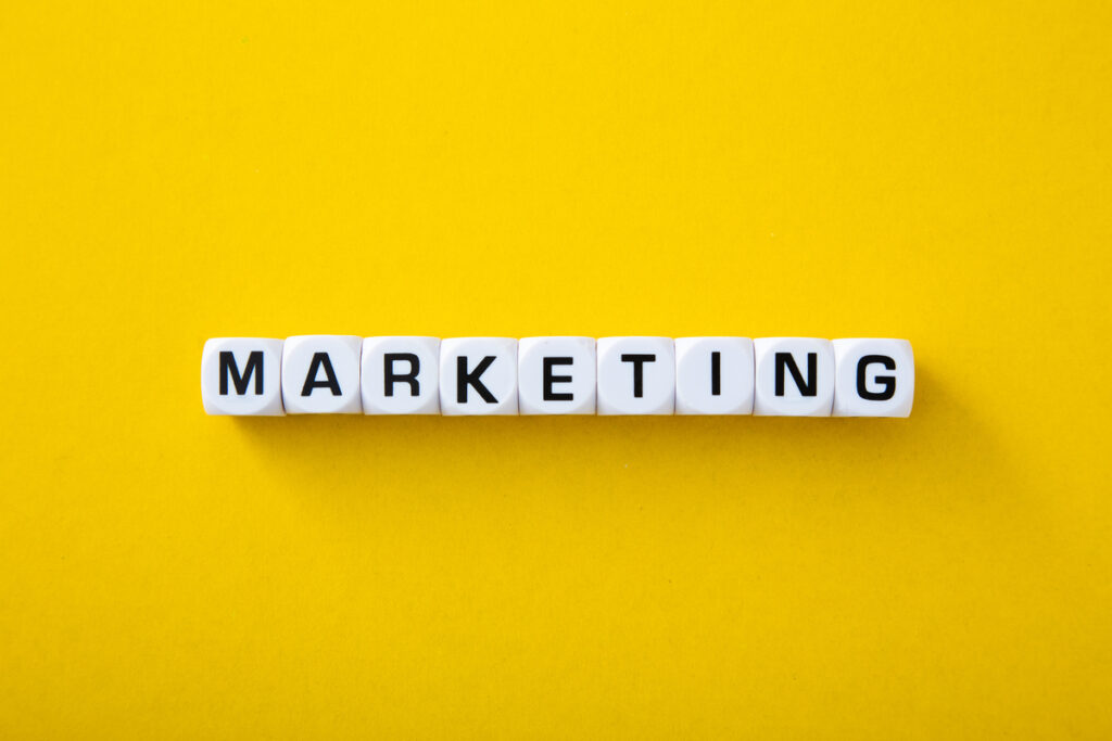 Dados com a palavra "marketing" escrita em fundo amarelo; saiba mais sobre mídia paga, mídia própria e mídia orgânica