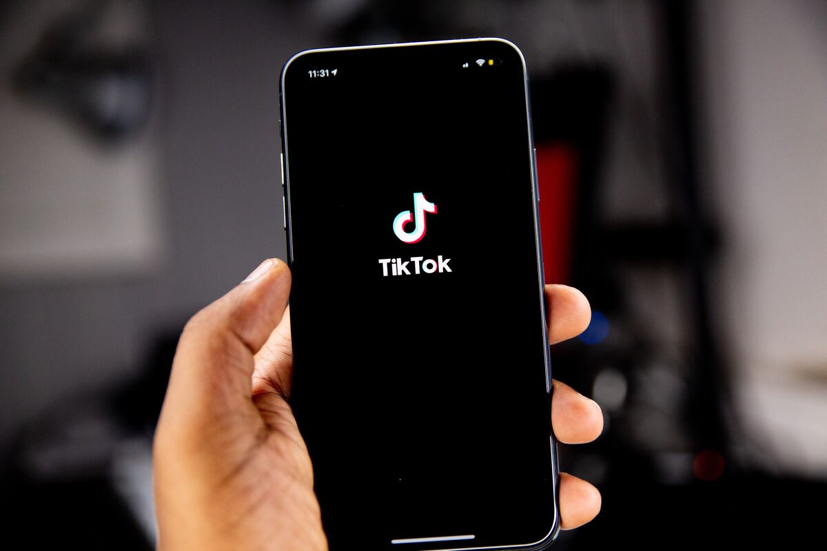 Pessoa segurando celular com aplicativo do TikTok sendo aberto