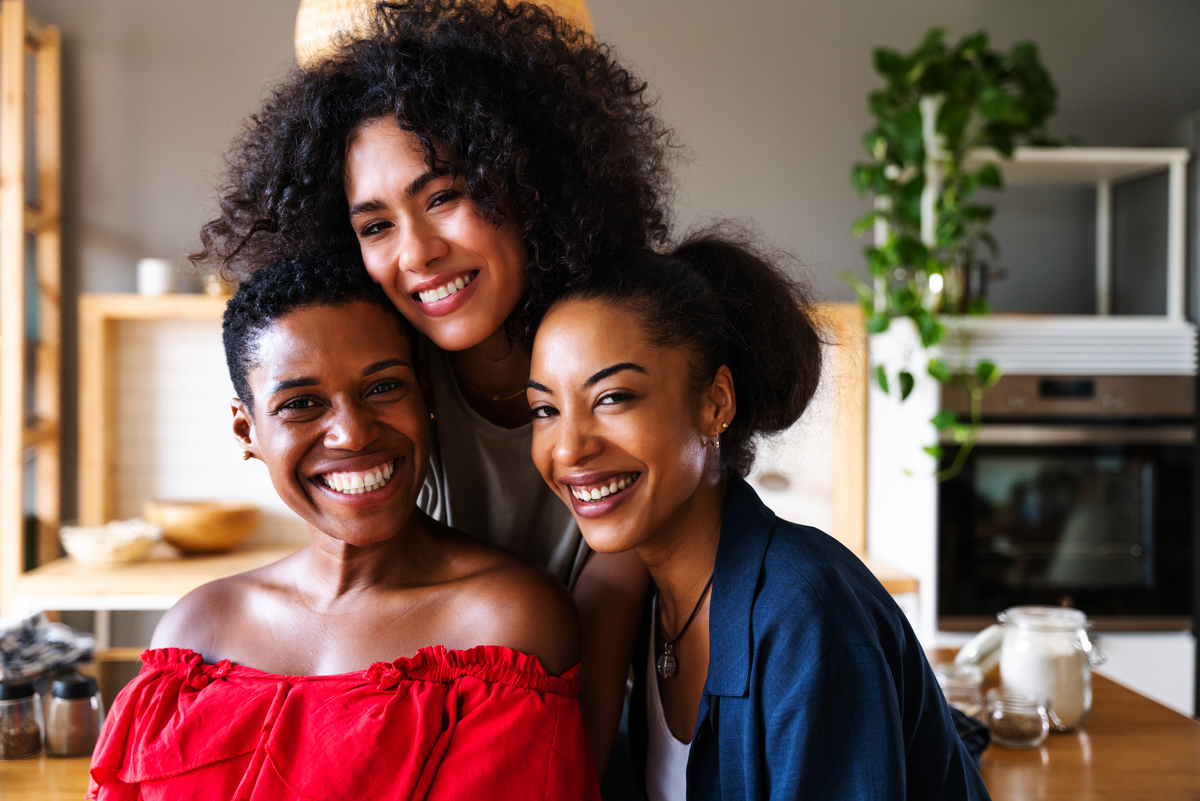 Três mulheres negras sorrindo para foto juntas