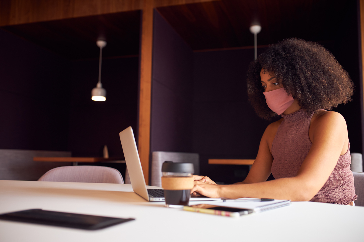 Mulher de negócios, trabalhando no computador usando máscara. Referência à pandemia