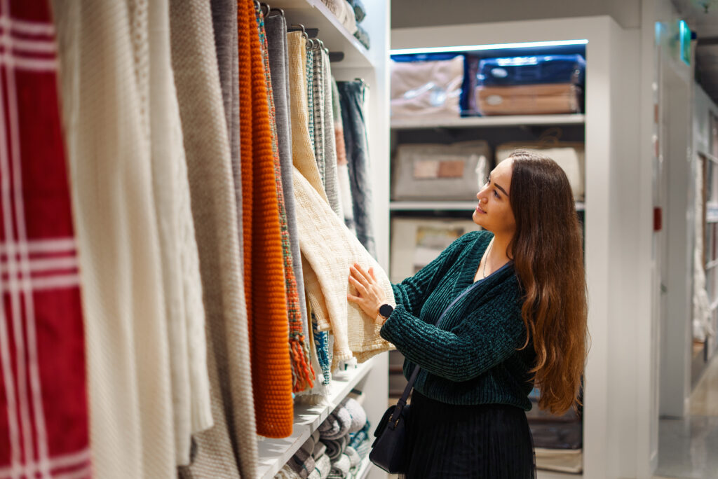 Mulher fazendo compras de produtos de cama, mesa e banho; varejo físico