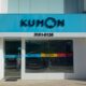 Fachada com logo azul do Kumon, com carinha no lugar do "O". Cursos