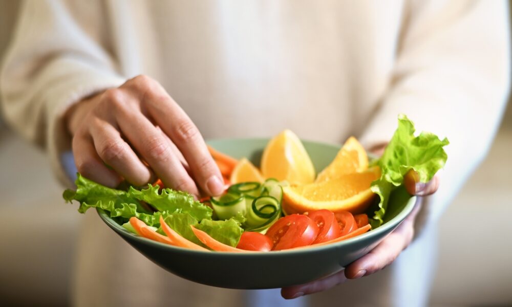 Pessoa organizando prato de salada; vegetarianismo