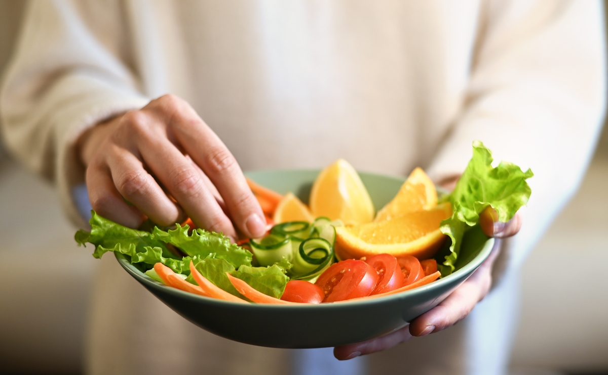 Pessoa organizando prato de salada; vegetarianismo