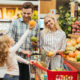 Família jovem feliz em pé com um carrinho e escolhendo frutas no supermercado