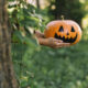 pessoa segurando abóbora de halloween para fora enquanto se esconde atrás de árvore