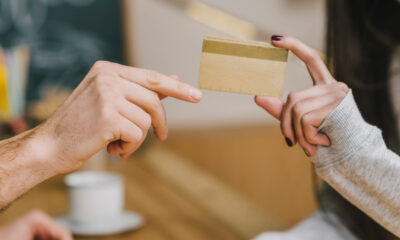 Mulher entregando cartão de crédito para outra. Close nas mãos