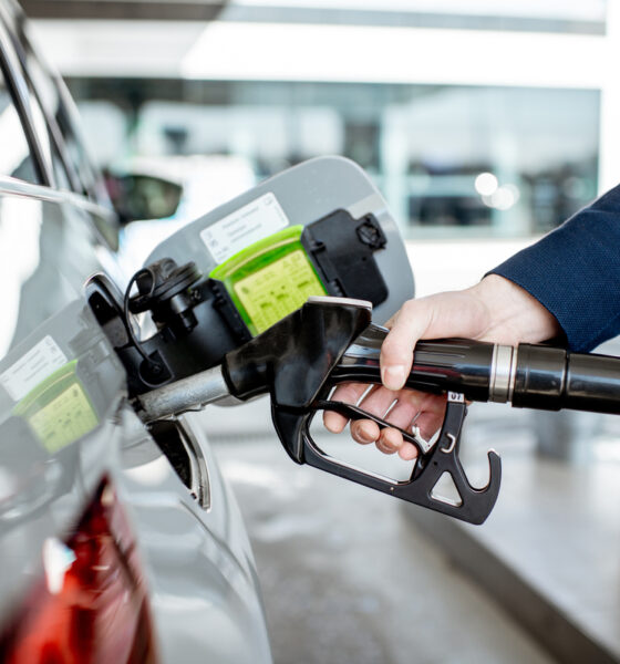 Homem reabastecendo carro com bomba de posto de gasolina.
