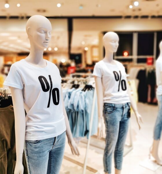Dois manequins femininos com camiseta branca e símbolo de porcentagem e calça jeans, em fundo de loja de roupas. varejo brasileiro
