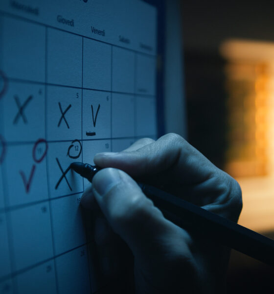 Mão marcando dias no calendário ilustra semana de quatro dias de trabalho; produtividade