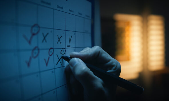 Mão marcando dias no calendário ilustra semana de quatro dias de trabalho; produtividade