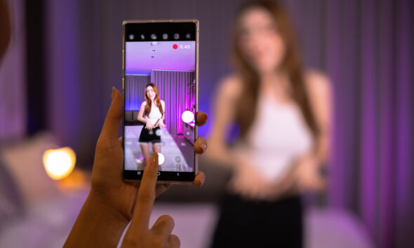 Jovens gravando vídeo de dança em celular; TikTok Shop é lançado nos EUA; Swarovski