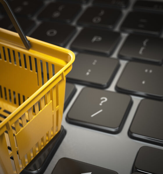Imagem com cesta de compras em cima de teclado de computador, simbolizando o conceito de e-commerce