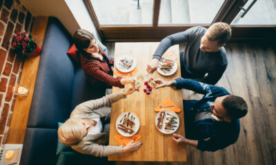 Quatro amigos vistos de cima, sentados à mesa em um restaurante e brindando; restaurantes