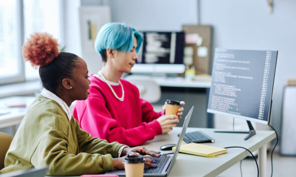 Menina negra com cabelo rosa trabalhando com menino asiático de cabelo azul, representando a geração Z no mercado de trabalho