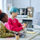 Menina negra com cabelo rosa trabalhando com menino asiático de cabelo azul, representando a geração Z no mercado de trabalho