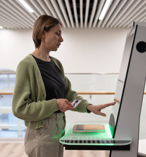 Mulher de meia idade usando terminal de autoatendimento no espaço da biblioteca digital, registrando livro, pesquisando e selecionando literatura ou navegando em catálogo. Tecnologias inovadoras em bibliotecas