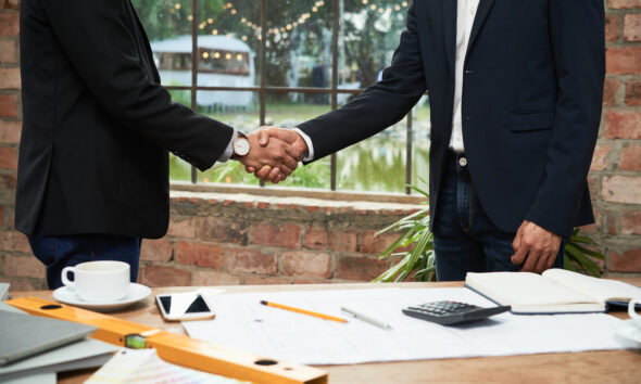 Parceiros de negócios apertando as mãos após reunião bem sucedida