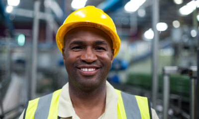 Trabalhador sorrindo em fábrica; trabalhadores ocupados