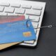 Anzol puxando cartões de crédito em cima de teclado de computador representando fraudes no e-commerce