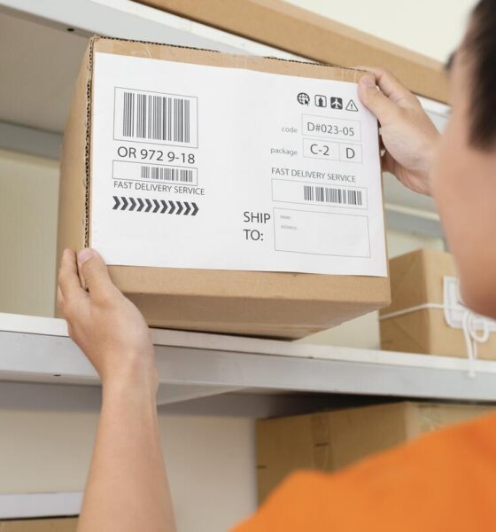 Homem jovem de camiseta laranja pega caixa com código SKU em estoque