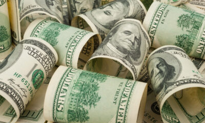 Notas de dólar enroladas em cima de uma superfície, para representar o preço do dólar; boletim focus