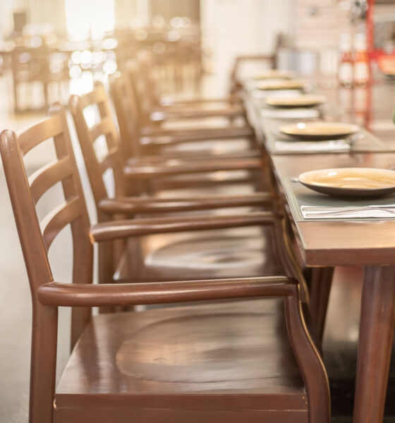 Mesa de restaurante com cadeiras e pratos vazios; bares e restaurantes