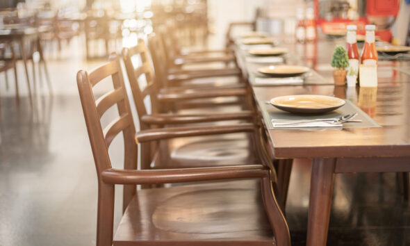 Mesa de restaurante com cadeiras e pratos vazios; bares e restaurantes