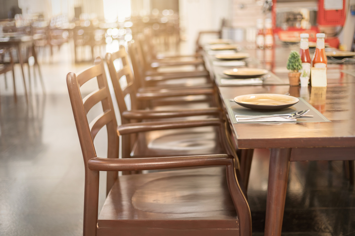 Mesa de restaurante com cadeiras e pratos vazios; bares e restaurantes