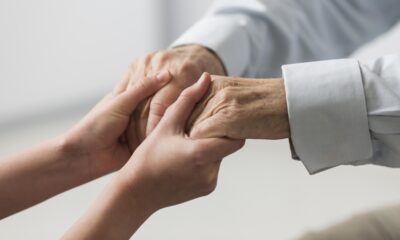 Cuidador de idoso segurando as mãos de pessoa idosa, em foto com close
