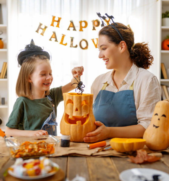 Feliz Halloween, mãe e filha esculpindo abóbora. Família se preparando para férias; consumo