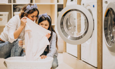 Mãe com filha lavando roupa na lavanderia self-service