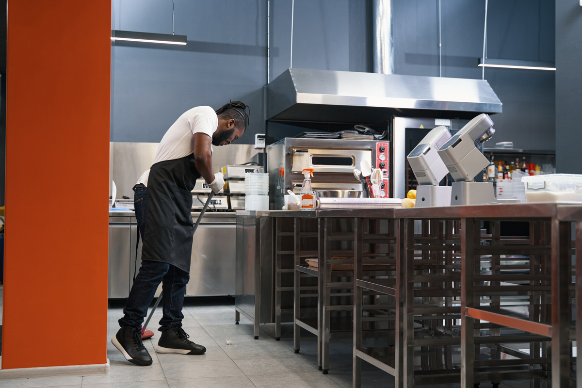 homem limpando cozinha de restaurante; bares e restaurantes