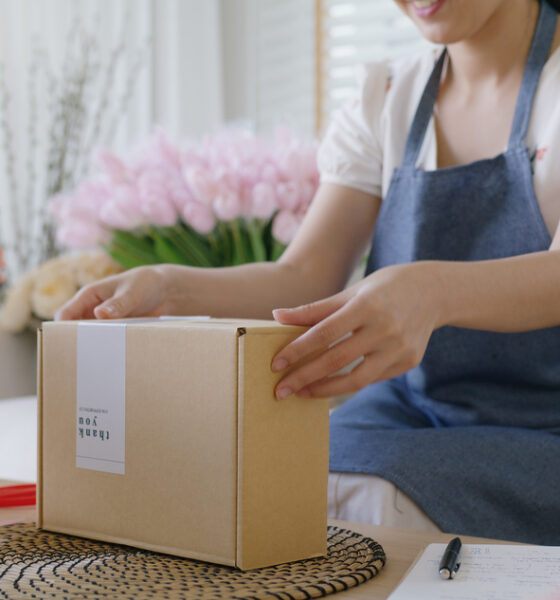 Mulher dona de pequena empresa embalando produto; pós-venda; prospecção