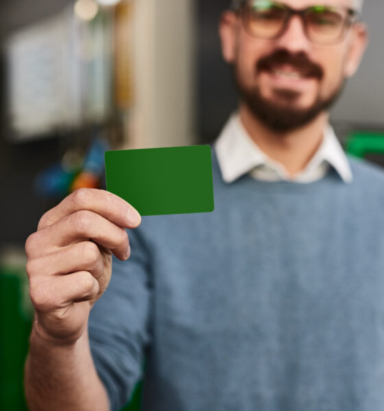 Foco suave do homem demonstrando cartão fidelidade verde em branco enquanto visitava posto de combustível durante o dia na cidade; ABEMF