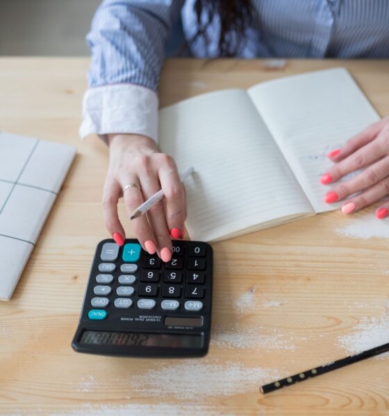 Mulher fazendo contas em calculadora e caderno