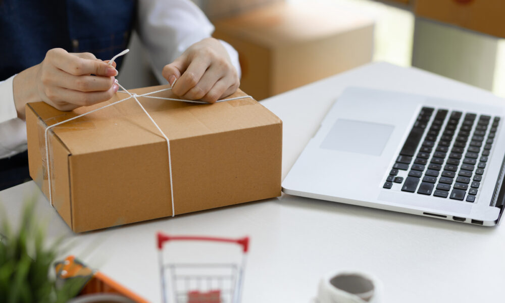 Pessoa amarrando uma caixa de entrega de produto; e-commerce