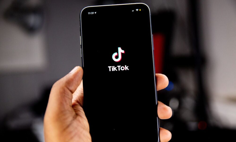Pessoa segurando celular com aplicativo do TikTok sendo aberto