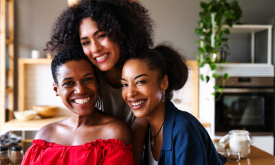 Três mulheres negras sorrindo para foto juntas