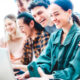 Cinco jovens sorrindo ao redor do computador, com a ideia de empreendedorismo social