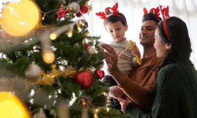 Família colocando decoração de natal em árvore com filho pequeno