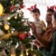 Família colocando decoração de natal em árvore com filho pequeno