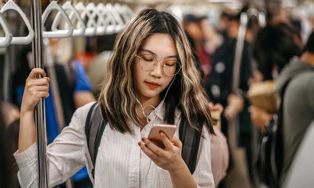 Adolescente da Geração Z utilizando o celular no metrô
