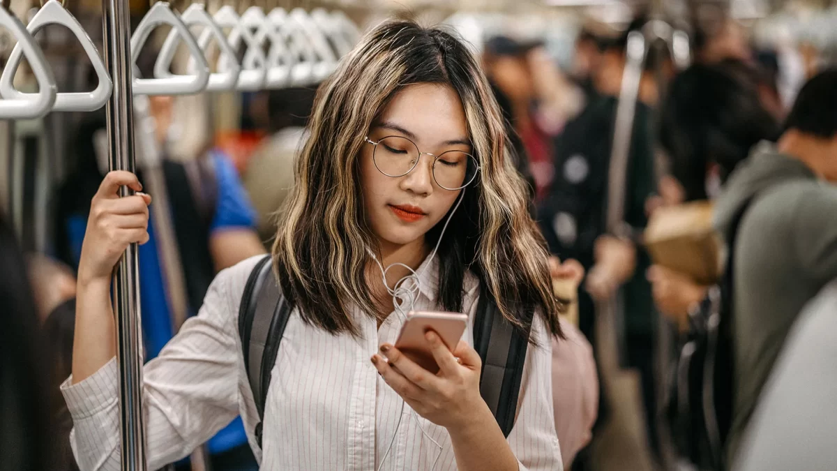 Adolescente da Geração Z utilizando o celular no metrô