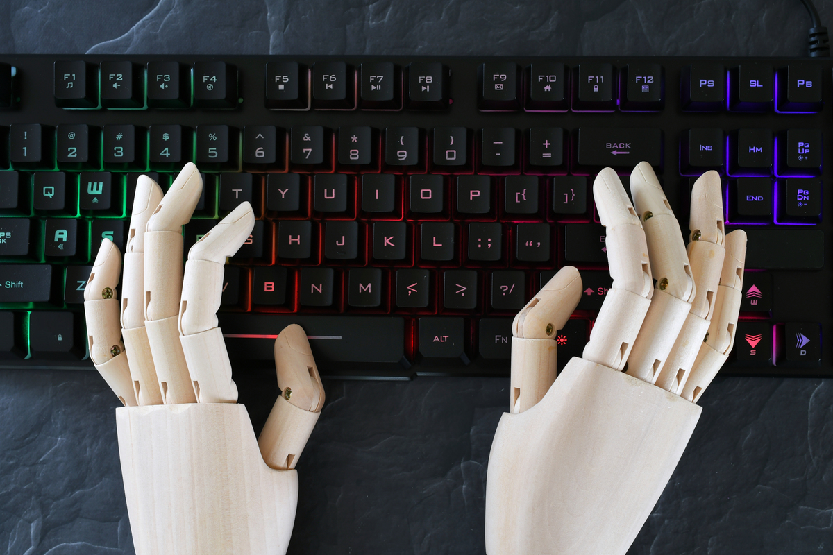 Mãos de robô digitando em teclado; conceito de inteligência artificial, IA