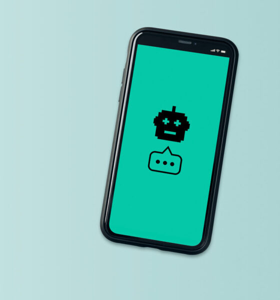 Celular com robô e balão com reticências, fundo verde. Representação de inteligência artificial no atendimento ao cliente; Botmaker